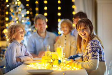 Christmas dinner. Family with kids at Xmas tree.