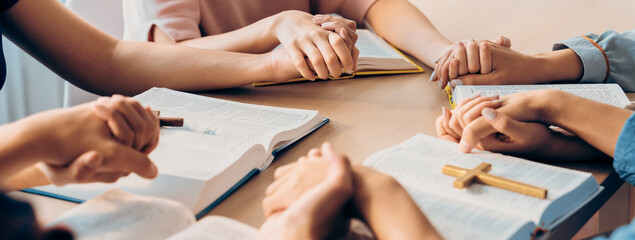 Cropped image of diversity people hand praying together at wooden church on bible book while hold hand together with believe. Concept of hope, religion, faith, god blessing concept. Burgeoning. - obrazy, fototapety, plakaty