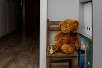 A teddy bear on a chair and next to it a jar with euro coins. a concept of savings for the child for the future. 