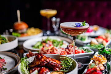 cocktail glass on table full of delicious food in plates in restaurant