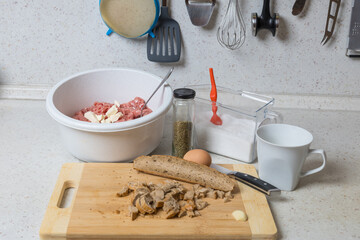 Raw materials for the production of baked meatloaf. Minced meat, cheese, bun, onion, egg, salt, marjoram.