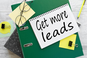 Get More Leads text on the page on a green folder near stickers on the work desk.