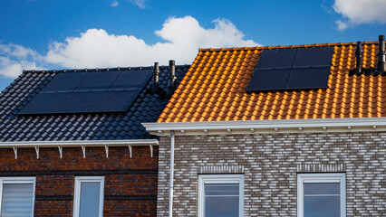 Fototapeta premium Newly built houses with solar panels attached to the roof against a sunny sky. black solar panels on a roof
