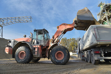 Wheel loader loads truck with gravel in a sand pit - transport and mining of building materials for...