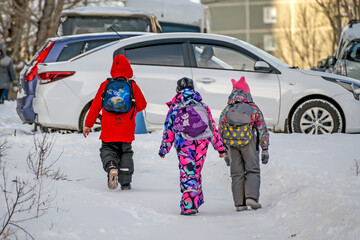 Schoolchildren walk along a snow-covered sidewalk on a winter day
