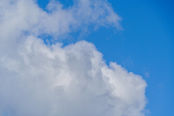 Cloudscape with white fluffy clouds in blue sky.