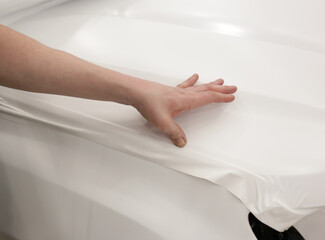 A specialist in wrapping a car with white vinyl film in the process of work. Car wrapping...