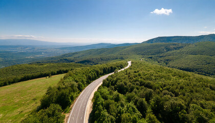 Fototapeta premium aerial view of countryside road passing through the green forest and mountain aerial view over mountain road going through forest landscape