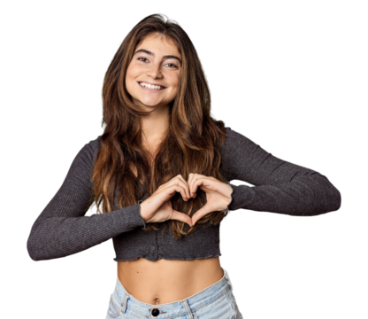 Young Caucasian woman in studio setting smiling and showing a heart shape with hands.