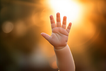 Baby waving his hand outside. Trying to catch the sun. Blurred warm background. In the style of Peach fuzz. High five!  - obrazy, fototapety, plakaty