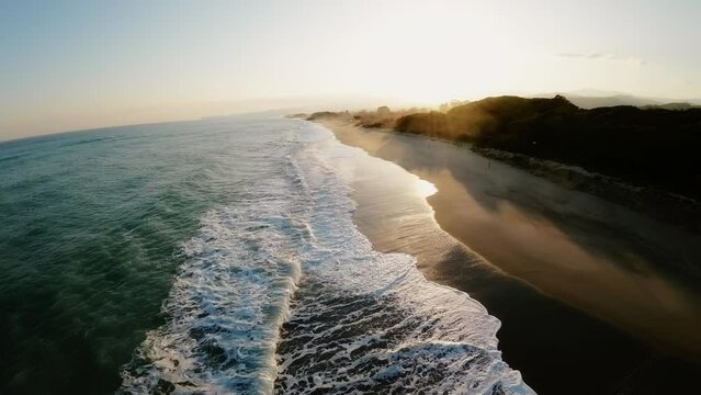 Waves of winter ocean crashing on the shore during susnet
