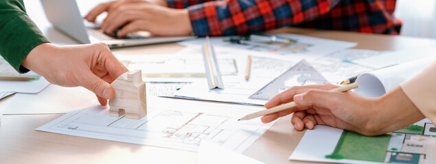 Skilled architect team using architectural equipment during colleague discussion about building design at meeting table with blueprint scatter around. Closeup. Focus on hand. Delineation.