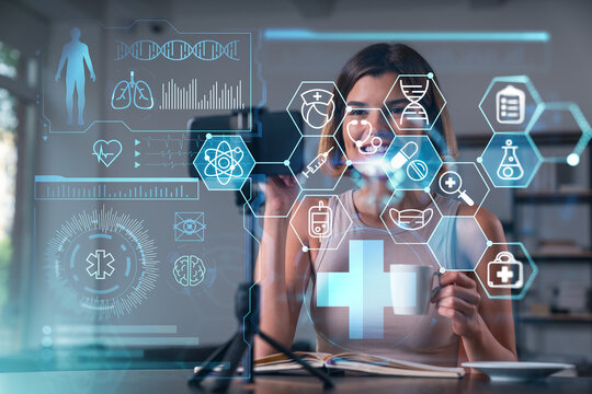 Happy woman is making video blog using smartphone on a tripod explaining with hands at office workplace. Concept of online stream, business education, conference call. Medical health care hologram