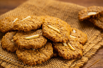 High angle view pile of crispy homemade coconut cookies on sackcloth on wooden board.
