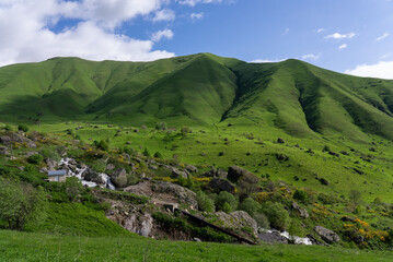 Fototapeta premium Landscape of Green Meadow on Mountains with Small Stream Under Blue Sky in Summer