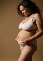 Authentic woman mother in lingerie, posing with postnatal naked belly with flaws stretch marks few...