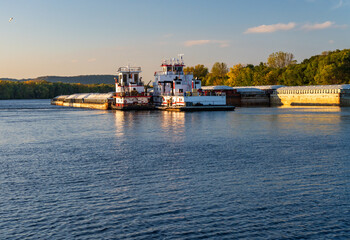Fototapeta premium Large grain shipment on Upper Mississippi in barge being pushed by two large pusher tugs on river