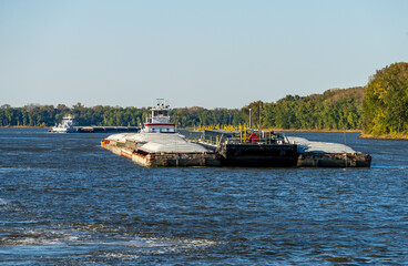Two large tug boats pushing rows of barges with grain and petroleum products down the Upper...