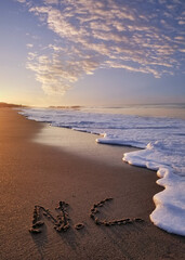 NC written in sand letters at sunrise on the beach in Oak Island North Carolina