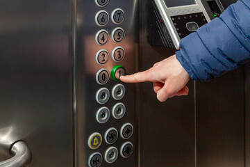 A man presses the floor button in the elevator of the business center - obrazy, fototapety, plakaty