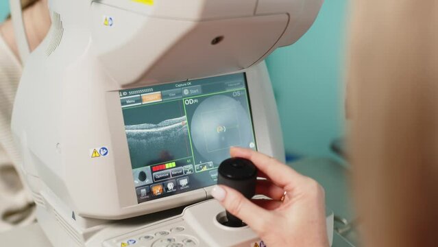 An ophthalmologist in a hospital examines the retina of the eye using modern technological medical equipment, a woman holds a joystick in her hands. Modern medical technologies.