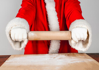 Ready to start cooking. Close-up Santa Claus in traditional costume holds a rolling pin.