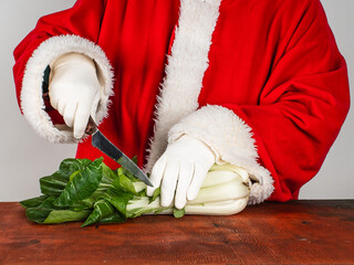 Santa Claus prepares a festive dish from fresh bok-choy. Healthy food concept.