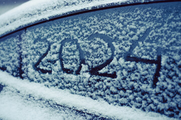 Snow-covered car window with numbers 2024