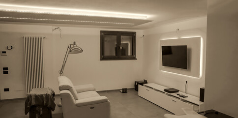 Moving to a new house. House interior. Ideas for basement living room. Entertainment room with TV and color led strips