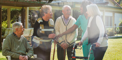 African nurse talking to two elderly retired couples outdoor in the rehab hospital garden....