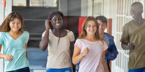 Happy multi ethnic group  of teenagers at school walking in the hallway. Happiness and lightheartedness concept