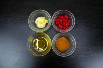 Cherry fruit, butter, chaat masala, and ghee are placed in a white bowl on a black background