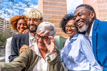 Mature businesswoman taking a selfie with colleagues outdoors