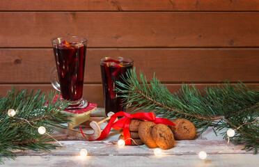Glasses of mulled wine, chocolate chip cookies, pine branches and glowing christmas lights. Selective focus. Christmas concept.