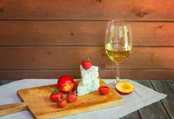 Glass of wine and cheese with  blue mold with strawberries and nectarines.