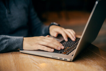 Close up of a male's hands typing on a laptop.