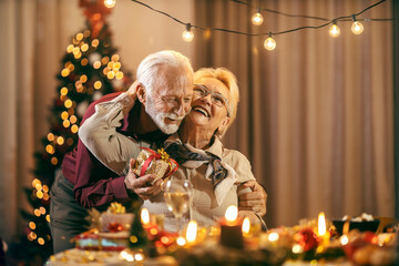 A senior man is surprising his wife with present on christmas and new year's eve at home.