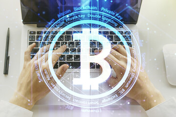 Double exposure of creative Bitcoin symbol hologram with hands typing on computer keyboard on background. Mining and blockchain concept