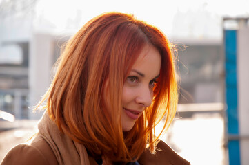 Autumn portrait of a young attractive long haired woman with red hair in the city. Beautiful...