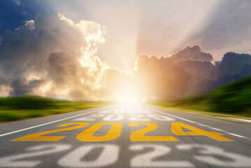 2024 New Year road trip travel and future vision concept. Number of the old year and New Year written on middle highway road in the empty asphalt road with sunset or sunrise light above asphalt road. - obrazy, fototapety, plakaty