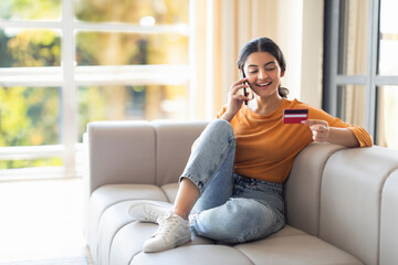 Online Banking. Smiling Indian Woman Talking On Cellphone And Holding Credit Card