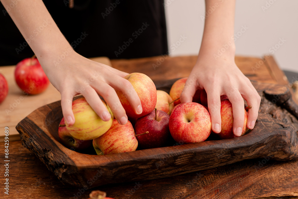 Wall mural A woman's hands and ripe red apples on a wooden board showcase the elegant simplicity of healthy eating, vegetarian principles, and the benefits of fruit consumption - Wall murals