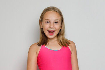 Surprised happy child girl with cute smile closeup posing on gray background