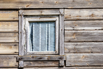 
an old wooden house with a wooden window pane in the wall and curtains behind it