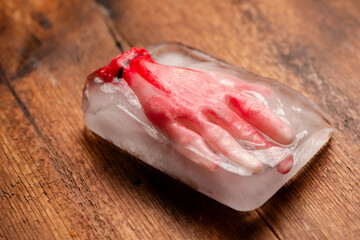 Frozen terror: A Halloween concept with an artificial human hand frozen in a block of ice on a...