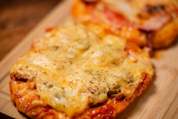 Culinary Delight: A duo of small home-baked pizzas, each adorned with flavorful ham and melted cheese, presented on a wooden cutting board