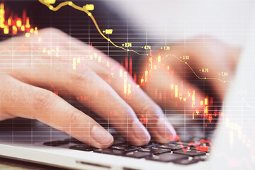 Close up of male hands using laptop keyboard with downward red candlestick forex chart with grid and index on blurry background. Crisis, falling stock market and recession concept. Double exposure.