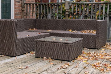 Outdoor wicker furniture in the fall with leaves on deck.