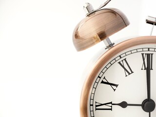 Copper twin bell retro alarm clock at 9 o clock on a white background with copy space to add text