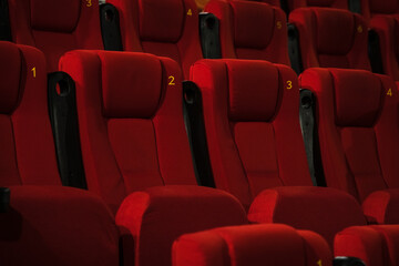 Obraz premium Empty comfortable red seats with numbers in the cinema